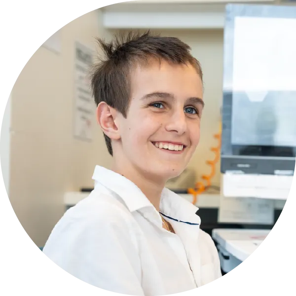 Artaban sitting in a hospital room wearing a white button-up shirt. A computer and medical equipment can be seen behind him